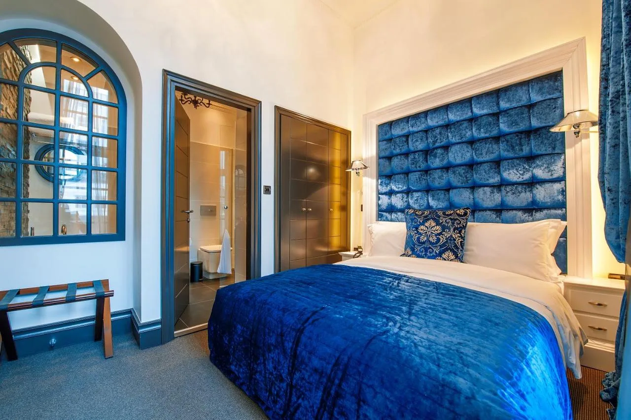 a bedroom with a large bed with a blue headboard at The Exhibitionist Hotel in London