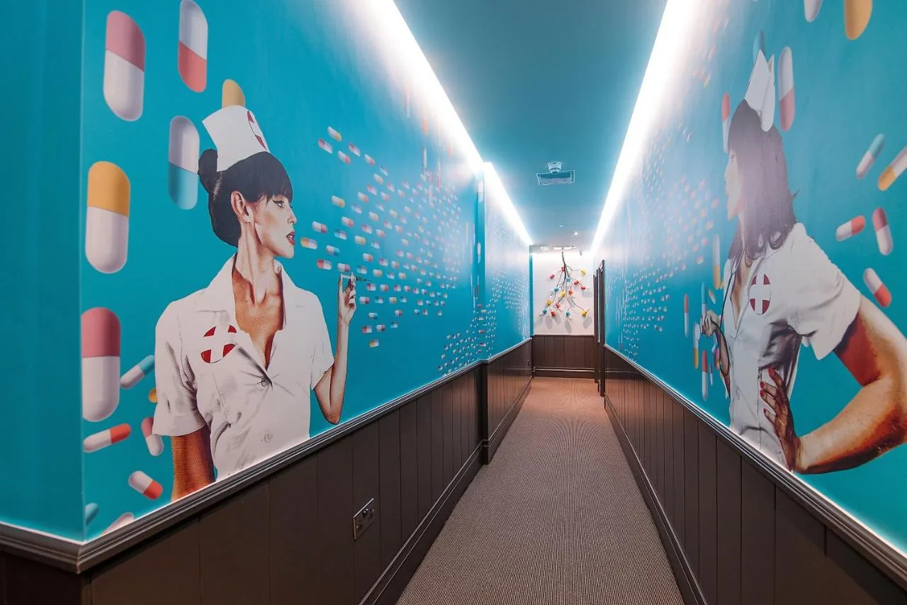 a hallway with a wall with paintings of food on it at The Exhibitionist Hotel in London